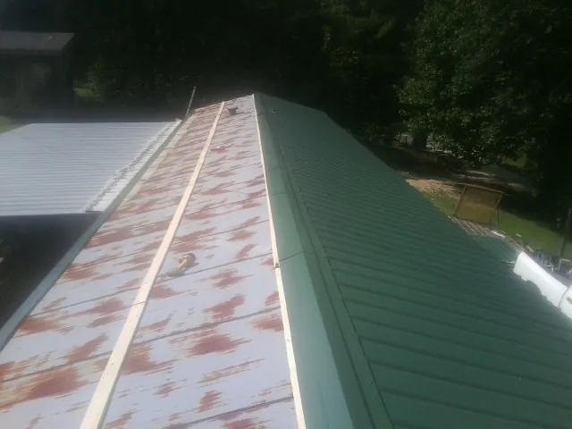Old rusted panels beside newly installed green metal roofing — Wind Damage Roof Repair by Roofing Brothers in Indian Lake Estates