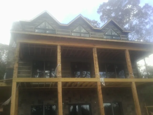 Dormers and porch framing on a large log home under construction — Roof Coating work by our crew in Indian Lake Estates