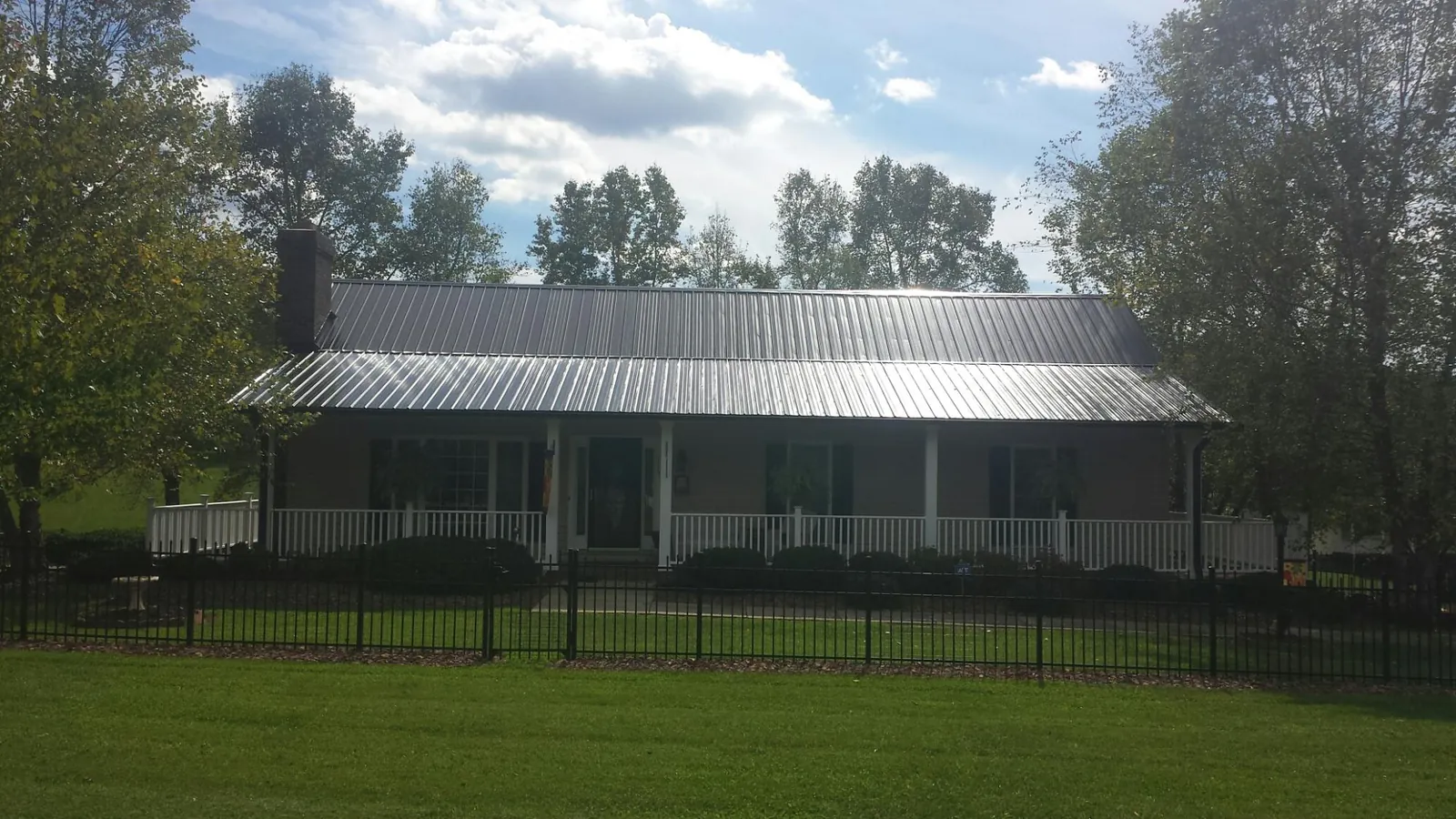 Gray metal roof on a brick ranch with a full width front porch — Gutter Guard Installation work by our crew in Indian Lake Estates