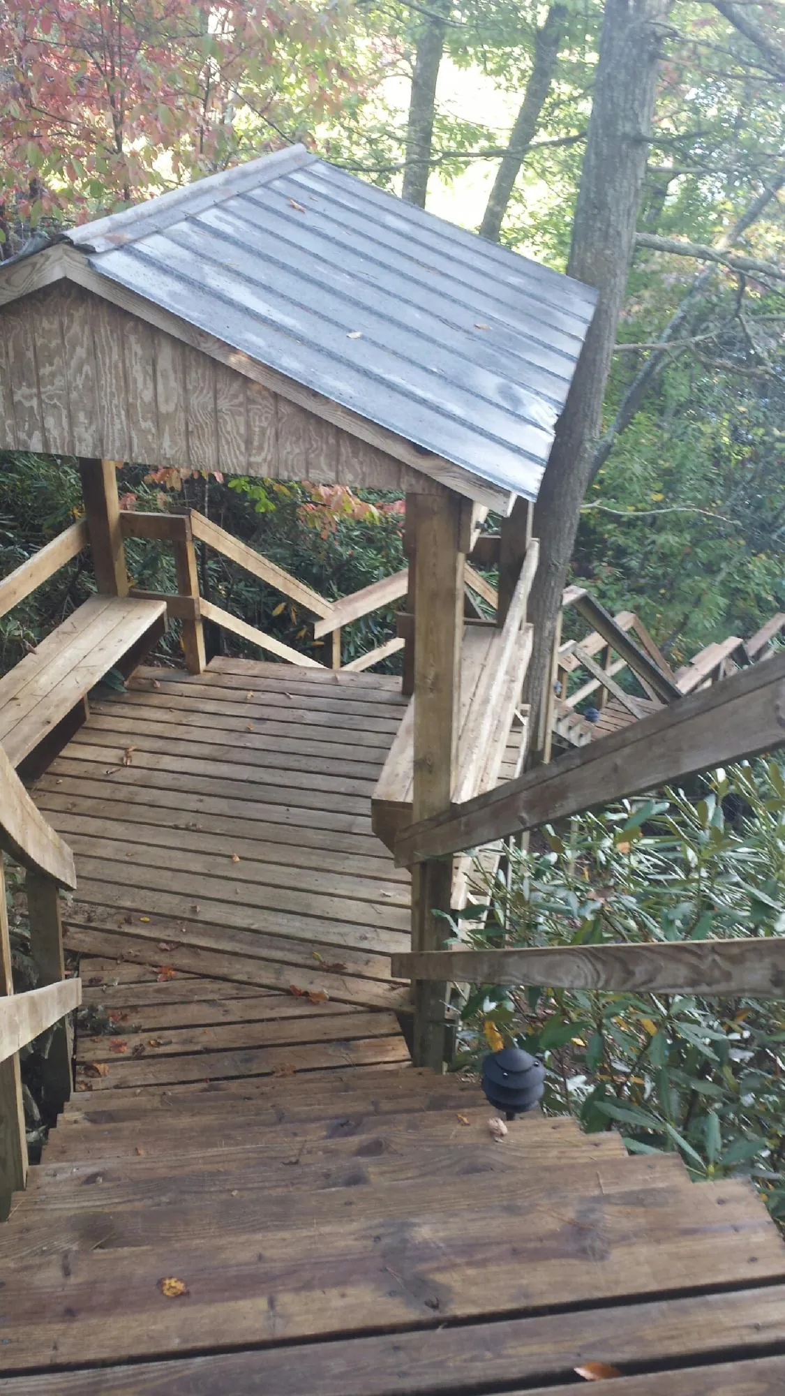 Metal roofed shelter over wooden steps on a wooded walkway — Skylight Repair & Installation work by our crew in Indian Lake Estates