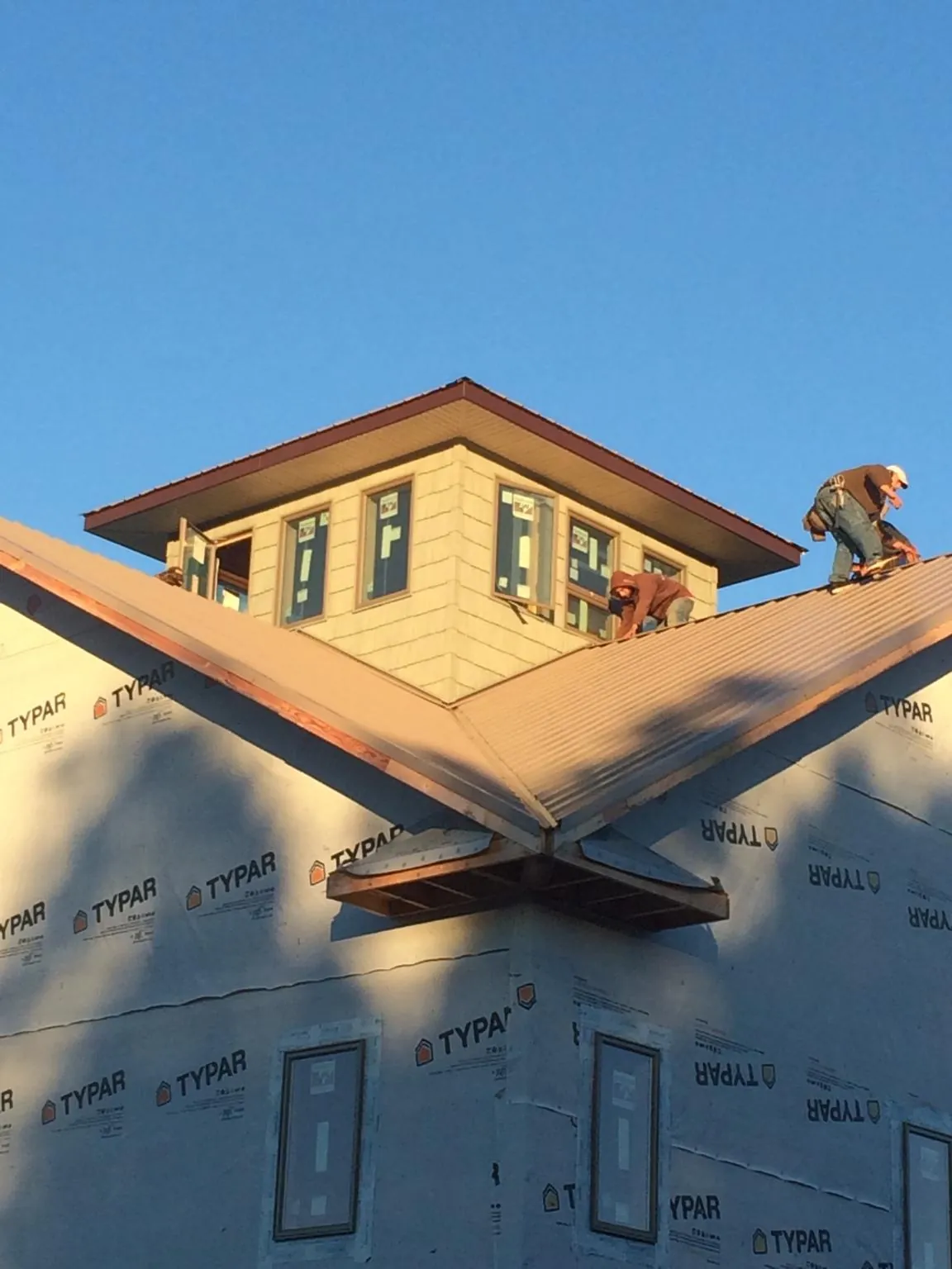 Roofers working around a rooftop cupola on a new metal roof at sunset — Roof Waterproofing in Indian Lake Estates by Roofing Brothers